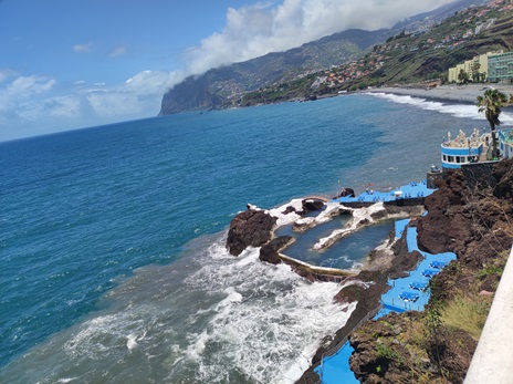 The natural pools of Doca do Cavacas in Funchal – Madeira A view of the Doca do Cavacas (Cavanas) lava pool complex in Funchal, Madeira, with terraces and the Cabo Girão cliff in the distance.