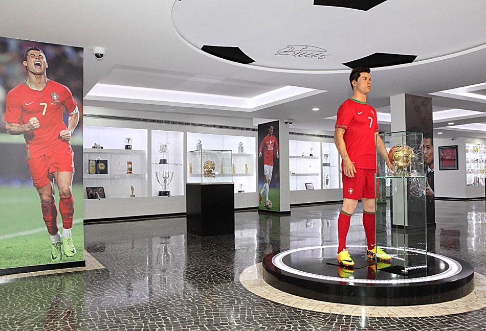 Wnętrze Museu CR7: Kolekcja pucharów i posąg Ronaldo na Maderze Figura Cristiano Ronaldo w muzeum CR7, wystawiona pośród zdobytych przez niego pucharów i medali.